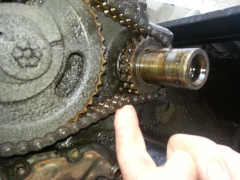 1994 Ford Bronco - A close-up view of an engine's timing chain and gears, with a finger indicating a specific point.