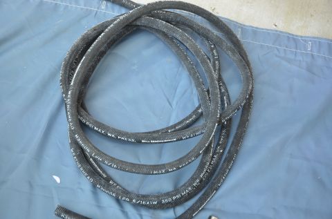 1979 Ford Bronco - A black braided hose with white text is coiled on a blue tarp.