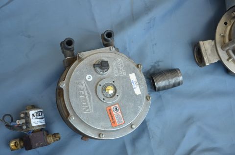 1979 Ford Bronco - Two propane system components, a regulator and a valve, are laid out on a blue surface.