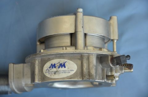 1979 Ford Bronco - Close-up of an aluminum carburetor, an oval MM logo with address details.