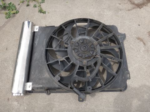 1995 Ford Taurus - A radiator fan and coolant tank assembly lies on a concrete surface.