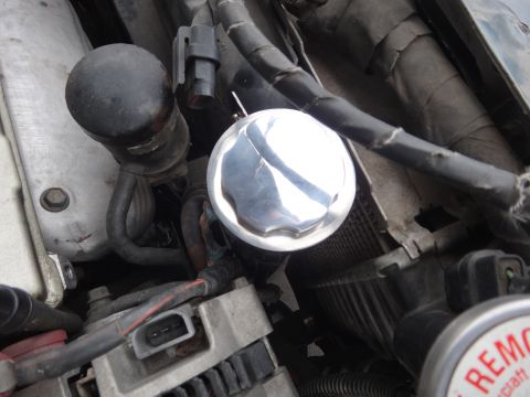 1995 Ford Taurus - Shiny metal cap on a car engine, surrounded by hoses and wiring.