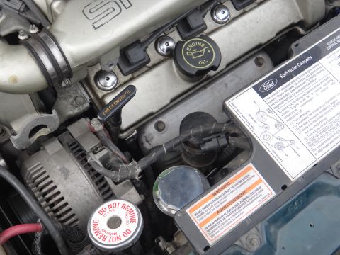 1995 Ford Taurus - The engine bay of a 1995 Ford Taurus, various labels and components.