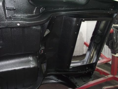 1967 Ford Mustang - The underside of a car's interior structure is visible, coated in black. A red stand supports part of the vehicle.