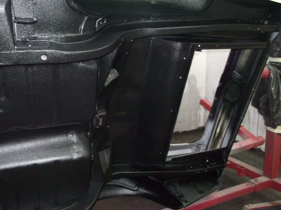 Underside of car interior showing structural components and black coating