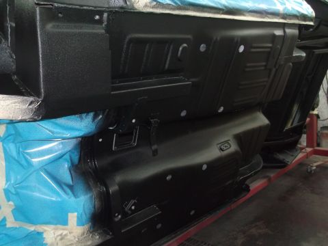 1967 Ford Mustang - The underside of a vehicle is shown with black protective coating and blue masking tape.
