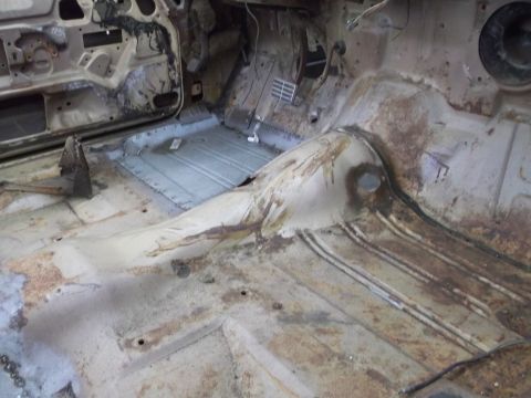 1964 Ford Galaxie - The interior floor of a car shows significant rust and exposed metal, indicating a state of disrepair or restoration.