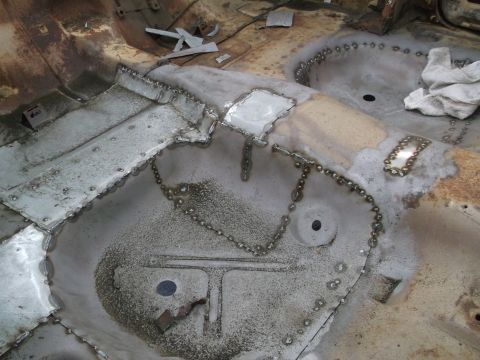 1964 Ford Galaxie - Newly welded patches on a car's floor pan indicate repair work.