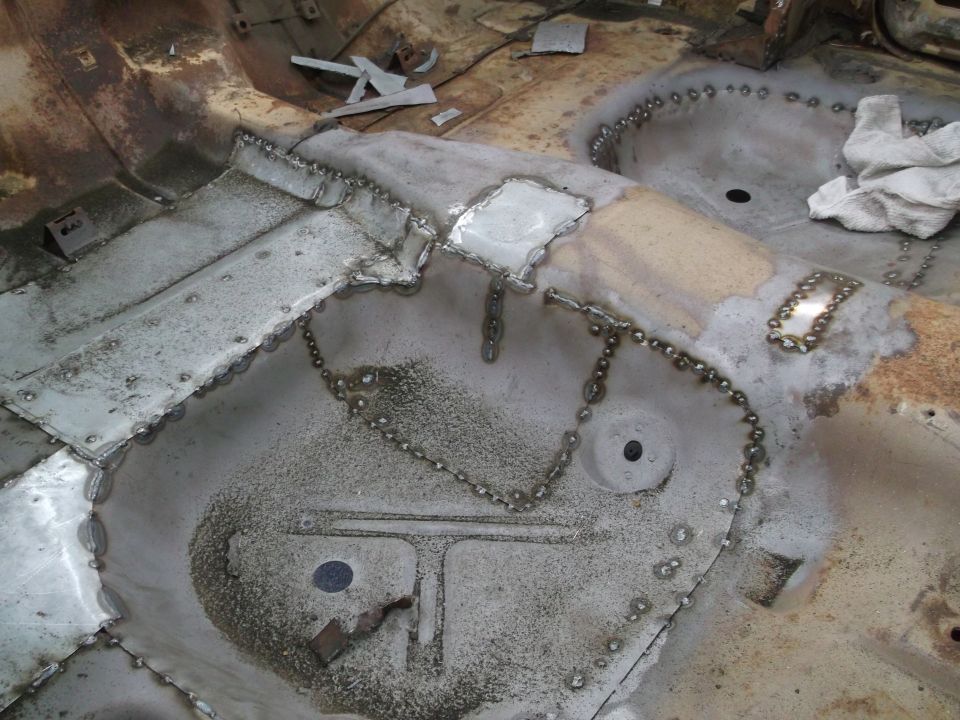 Car floor pan with new metal patches and spot welds