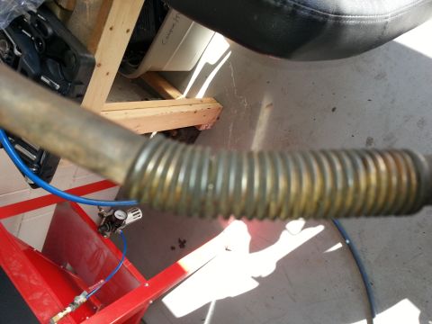 1994 Ford Bronco - A close-up view of a corrugated metal pipe attached to red equipment with a blue hose and gauge.