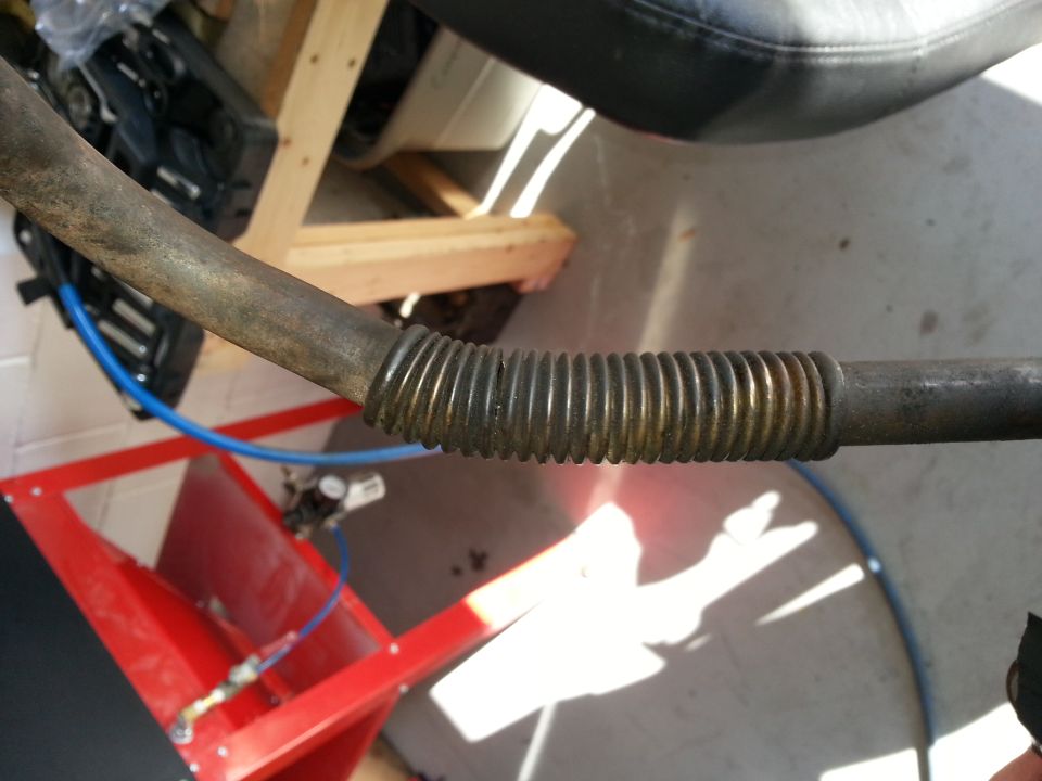 Corrugated metal pipe with a blue hose connected to a red metal stand