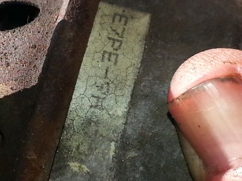 1994 Ford Bronco - A close-up view of a metal component with a partially legible label, showing some text and cracks.