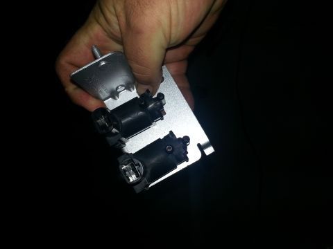 1994 Ford Bronco - A hand holds a metal bracket with two electrical connectors, likely a vehicle part.