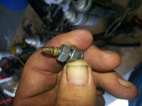1994 Ford Bronco - A close-up shows a hand holding a small metal component with hexagonal nuts and a pointed brass end.