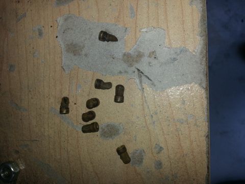 1994 Ford Bronco - Small metal parts are laid out on a wooden surface, with some grey material visible.