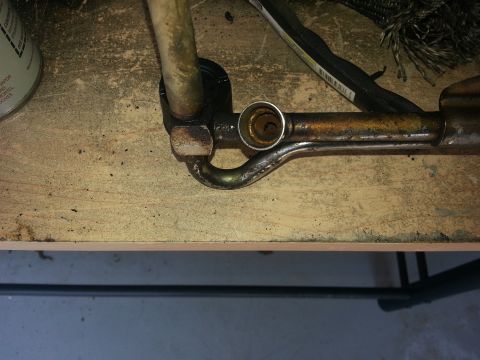 1994 Ford Bronco - Metal pipe fitting on a workbench, likely a component from a vehicle.