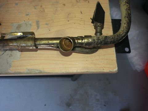 1994 Ford Bronco - A close-up view of a corroded metal pipe assembly with a small black flap attached.