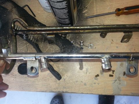 1994 Ford Bronco - Close-up of a disassembled fuel rail, showing the injectors removed and the metal rail itself.