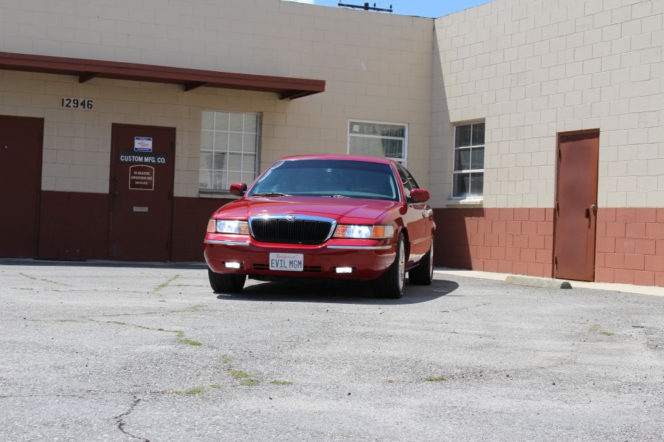 Red Mercury sedan parked at angle in a lot beside a tan building