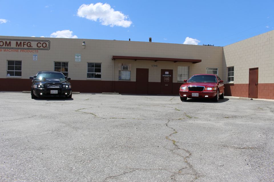 Black sedan and red Mercury sedan parked apart in a lot before a tan building