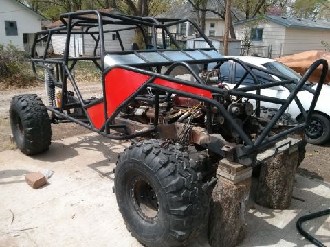 1986 Ford Bronco - This custom buggy is in a state of construction, a roll cage, large off-road tires, and red body panels.
