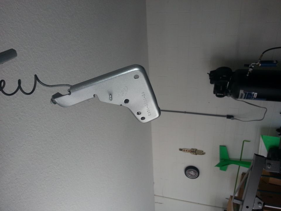 Metal bracket with Ford logo and part number E9TA-7B114-BA, attached to a wire
