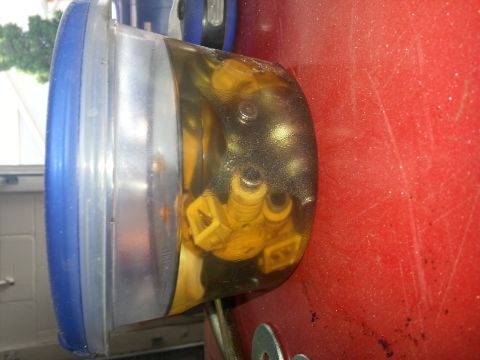 1994 Ford Bronco - Close-up of yellow-topped fuel injectors within a transparent casing, attached to a red panel.