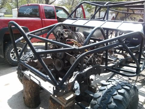 1986 Ford Bronco - Custom off-road buggy frame and engine assembly, with a red pickup truck parked nearby.