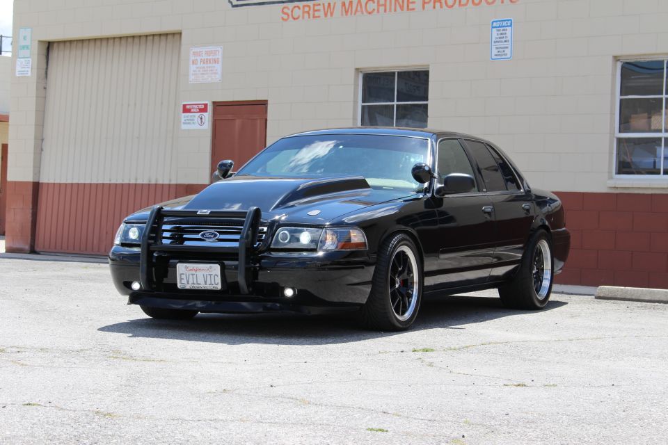 Lowered black Ford sedan with brush guard and black wheels, EVIL VIC plate