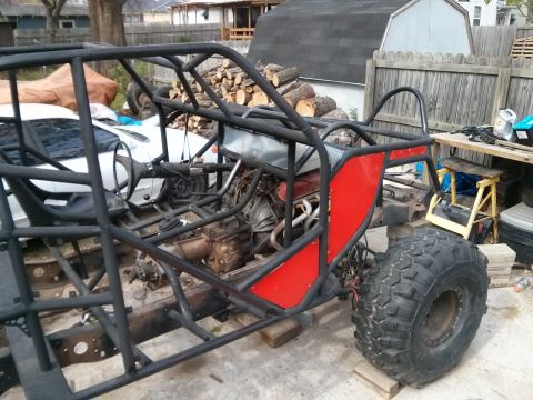 1986 Ford Bronco - A custom-built buggy frame with a roll cage and large off-road tires is shown in a backyard setting.