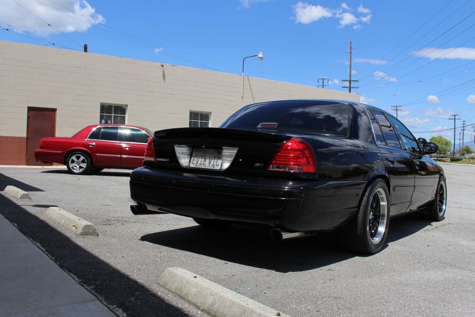 Rear three-quarter of a black sedan with spoiler, red Mercury sedan in background