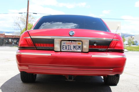 2003 Ford Crown Victoria - Close rear shot of a red Mercury sedan highlighting its taillights, chrome bumper, and California EVIL MGM license plate.
