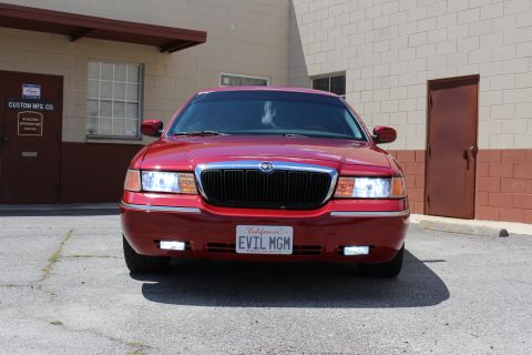 2003 Ford Crown Victoria - Red Mercury sedan front end with chrome grille, illuminated headlights, and a California EVIL MGM license plate.