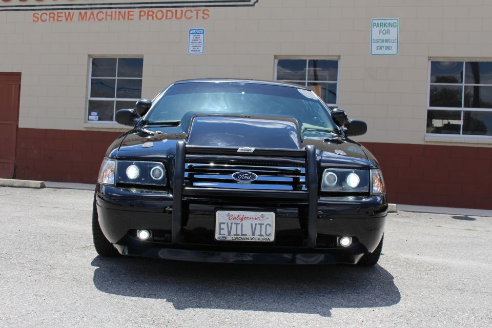 Front view of black Ford Crown Victoria with grille guard and EVIL VIC California plate