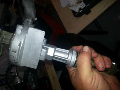 1994 Ford Bronco - A hand holds a silver distributor, a key component for ignition systems, against a dark background.