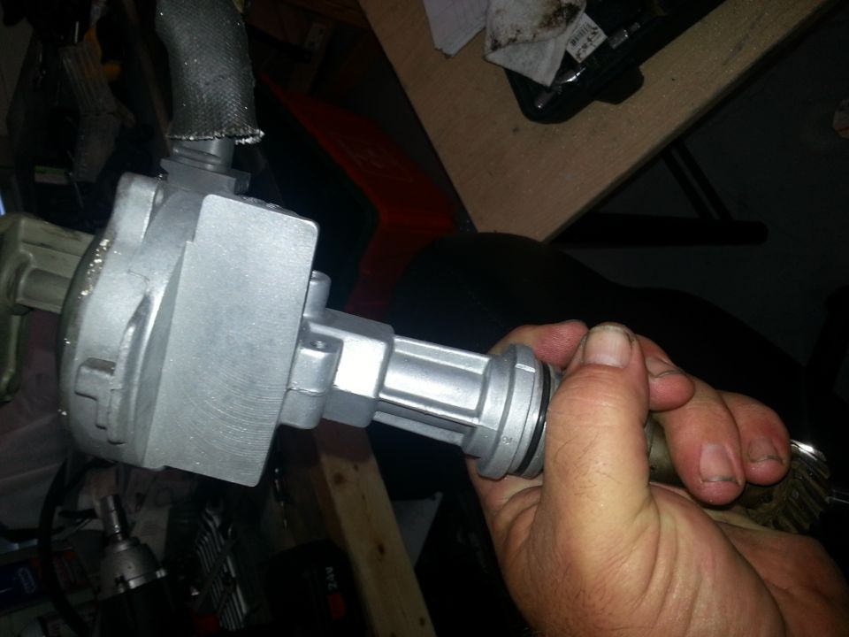Hand holding a silver distributor with black hose attached