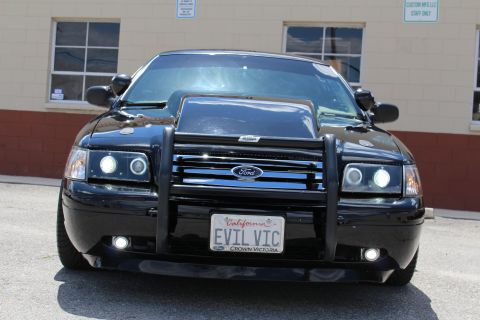 2003 Ford Crown Victoria - close head-on view of a black Ford Crown Victoria showing projector headlights, grille guard and a California EVIL VIC plate.