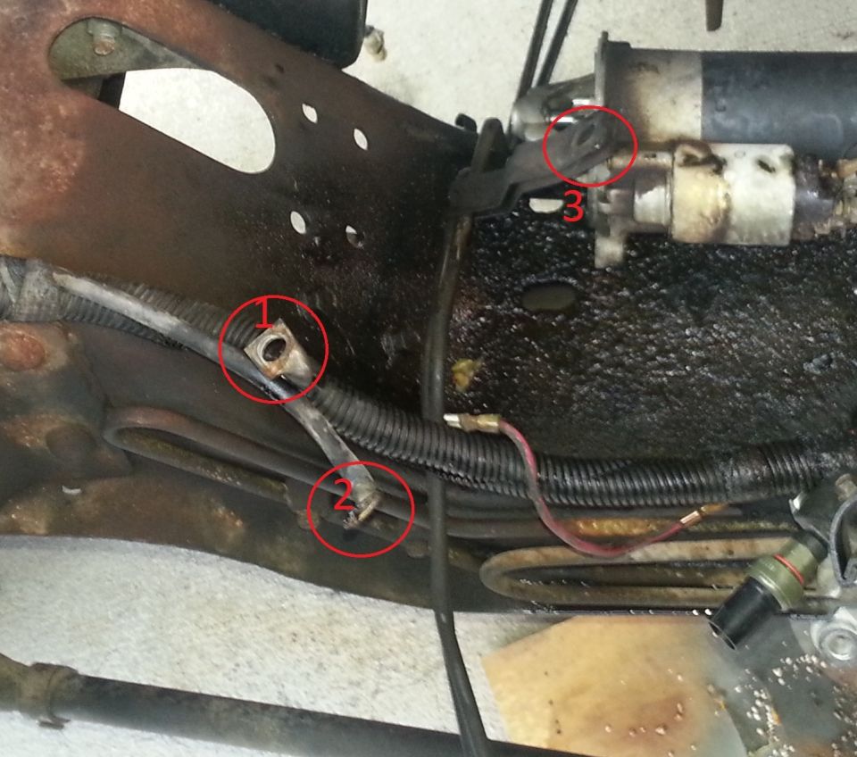 Close-up of engine starter motor with red circles highlighting electrical connections