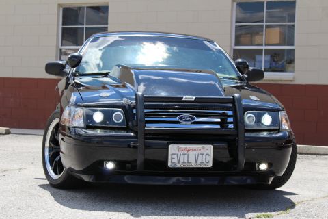 2003 Ford Crown Victoria - Head-on view of a black Ford Crown Victoria with a Ford-badged grille guard, halo lights and an EVIL VIC California license plate.