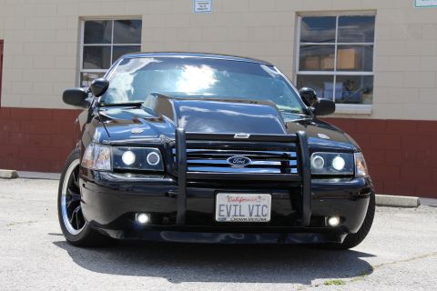 2003 Ford Crown Victoria - black Ford Crown Victoria viewed head-on with its grille guard bearing a Ford oval and an EVIL VIC Crown Victoria plate.