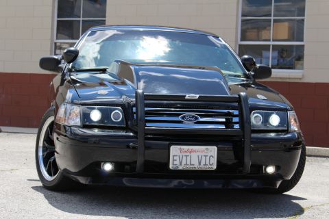 2003 Ford Crown Victoria - Front view of a lowered black Ford Crown Victoria showing halo headlights, grille guard with Ford oval and an EVIL VIC plate.