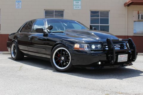 2003 Ford Crown Victoria - Front three-quarter of a black Ford Crown Victoria with grille guard, chrome-lip wheels and a California EVIL VIC plate.