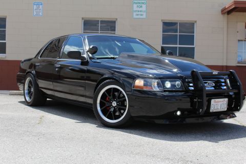 2003 Ford Crown Victoria - lowered black Ford Crown Victoria angled in a lot, showing grille guard, tinted glass and an EVIL VIC license plate.