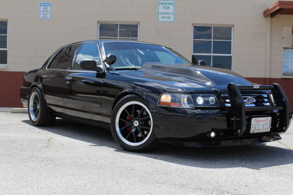 Black Crown Victoria front three-quarter view with grille guard and dark wheels