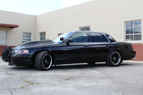2003 Ford Crown Victoria - lowered black Ford Crown Victoria shown in side profile with a push bumper and chrome multi-spoke wheels.