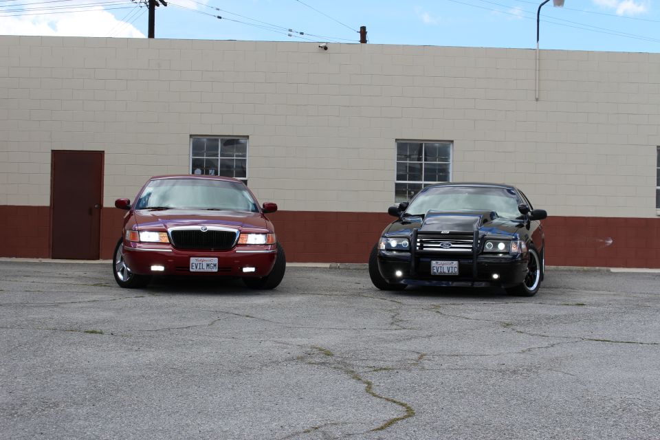 Maroon Mercury Grand Marquis and black Ford Crown Victoria parked side by side, front view
