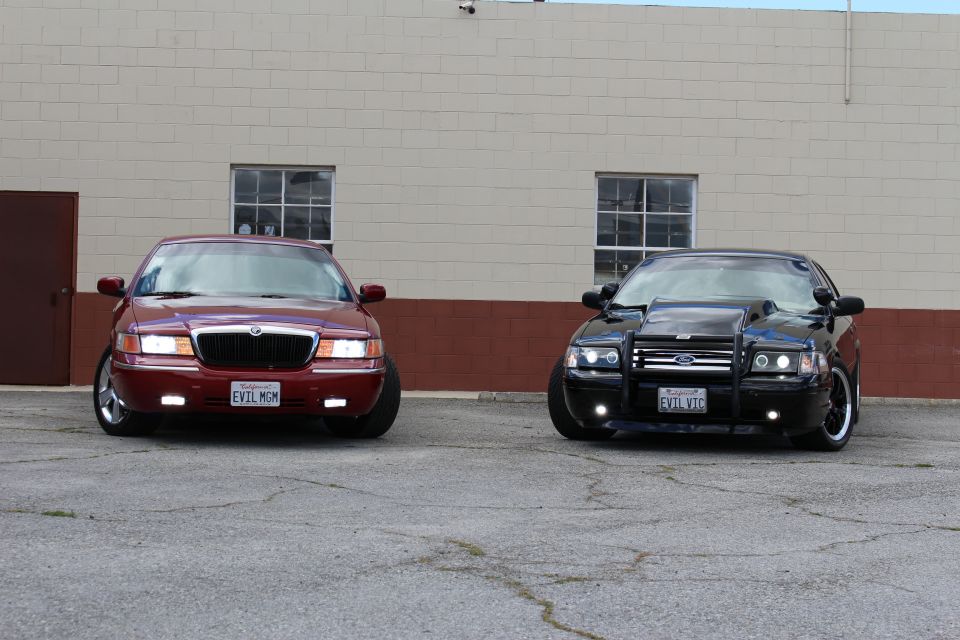 Front view of maroon Mercury sedan and black Ford sedan with grille guard, parked side by side