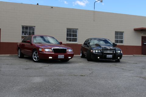2003 Ford Crown Victoria - Front three-quarter shot of a lowered maroon Mercury beside a black Crown Victoria fitted with a chrome push bar.