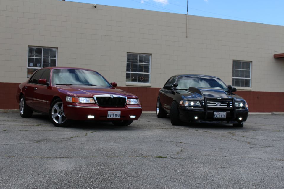 Maroon Mercury Grand Marquis and black Crown Victoria with grille guard, parked