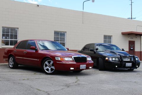 2003 Ford Crown Victoria - Three-quarter front view of a lowered maroon Grand Marquis with a black Crown Victoria beside it on cracked pavement.